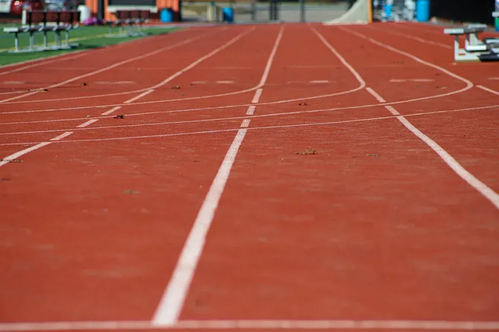 Pusta bieżnia lekkoatletyczna z oznaczonymi torami, na której mierzy się przebiegnięty dystans
