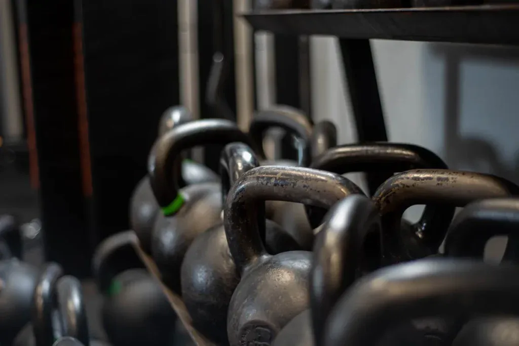 Kettle w różnych ciężarach na stojaku; za ciężki kettlebell na start to częsty błąd mężczyzn