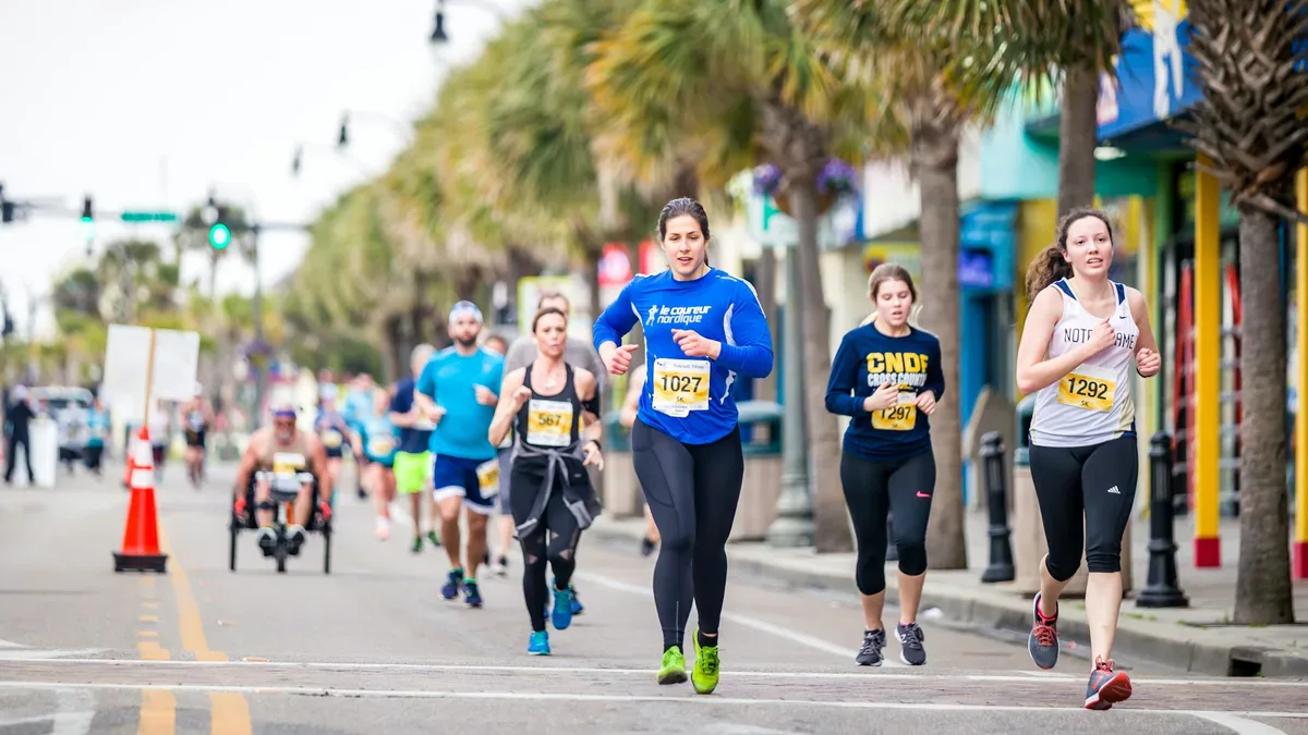 Trening do maratonu w praktyce: amatorzy z numerami startowymi biegną w środku stawki
